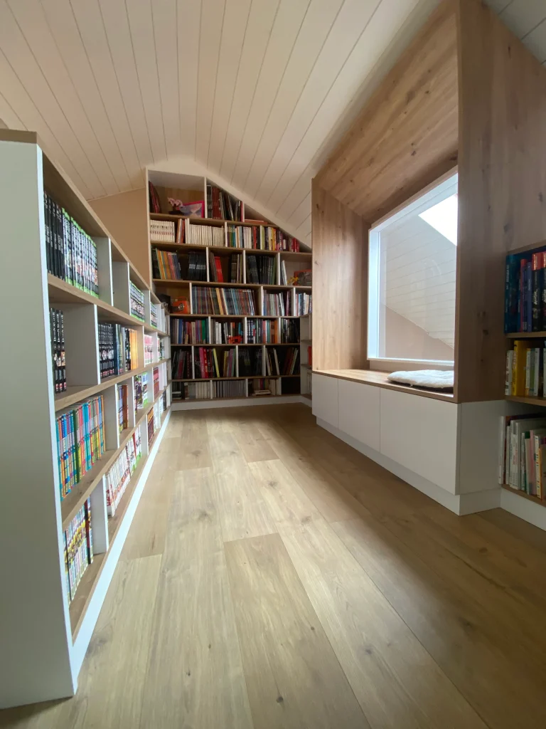 Aménagement bibliothèque sous rampants avec coin lecture