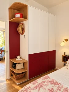 Dressing intégré sur-mesure rouge et blanc avec coin vestiaire, crochets et étagères arrondies en chêne